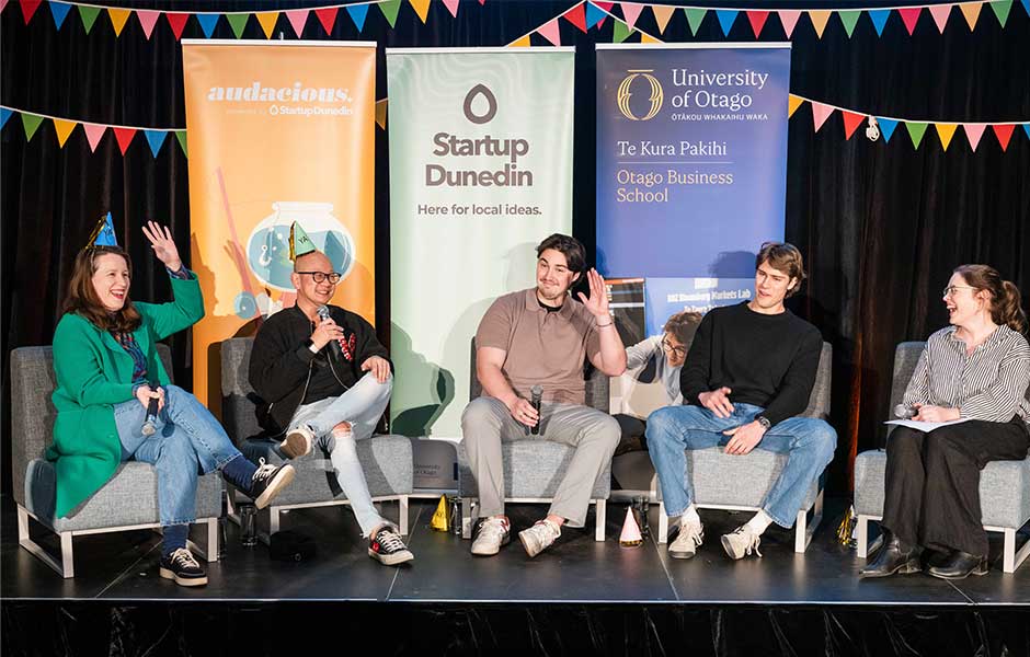 five people sitting in chairs on a stage