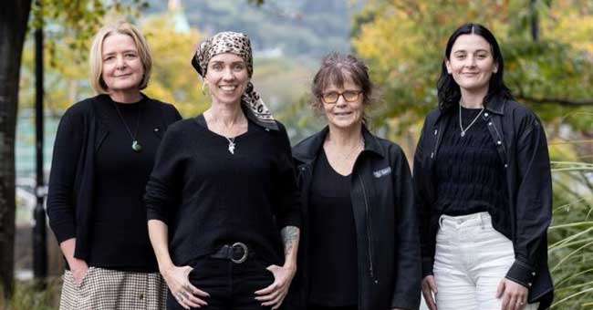 Four women standing on a footpath 