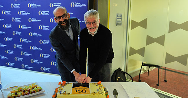 two men cutting a cake
