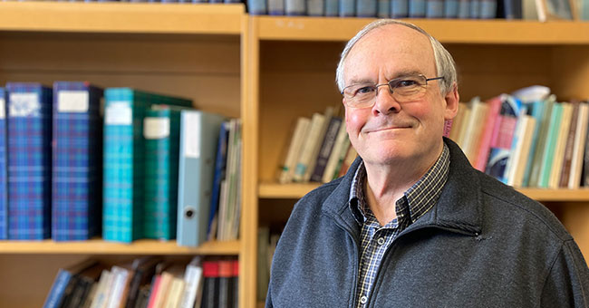 A man standing in front of a bookcase 