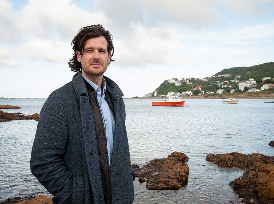 A man standing in front of a small harbour with a boat in it
