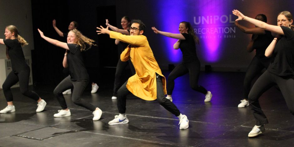 A group of students performing a dance routine on a stage.