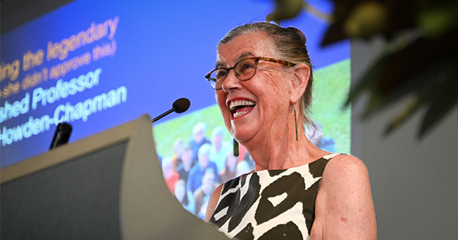 Philippa Howden-Chapman smiles at a podium.
