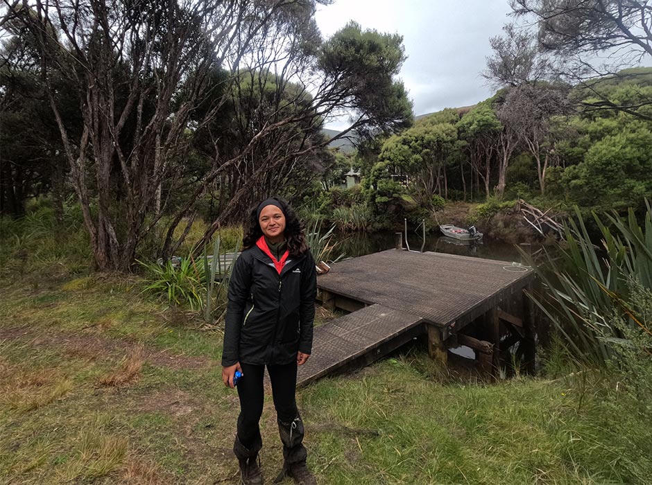 A woman stands outside in nature.