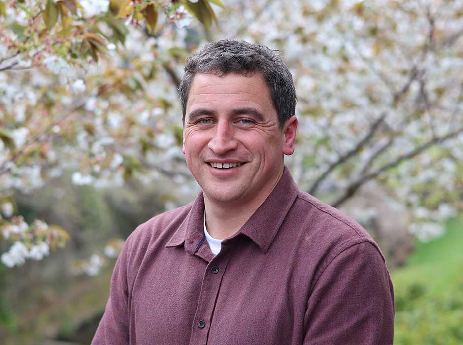 head and shoulders of a man standing in front of a blossoming tree