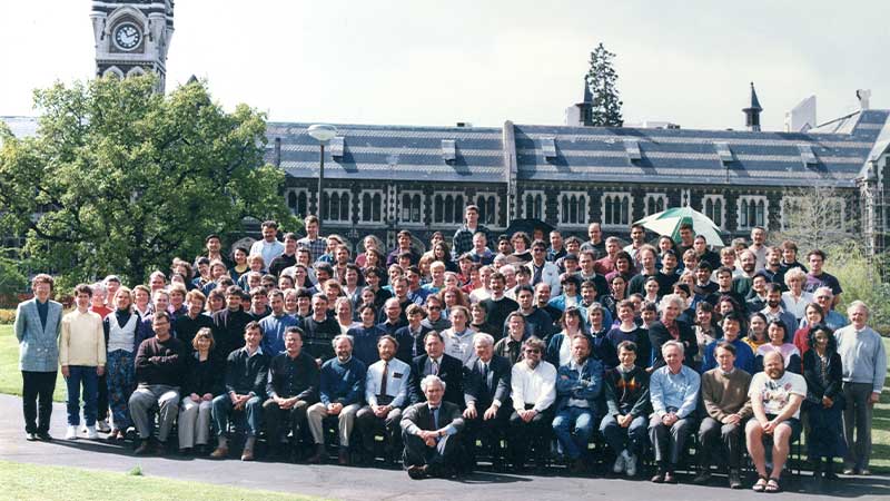 several rows of people standing for a photo with the clocktower in the background