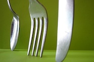 Photo of spoon, fork and knife standing against a green background