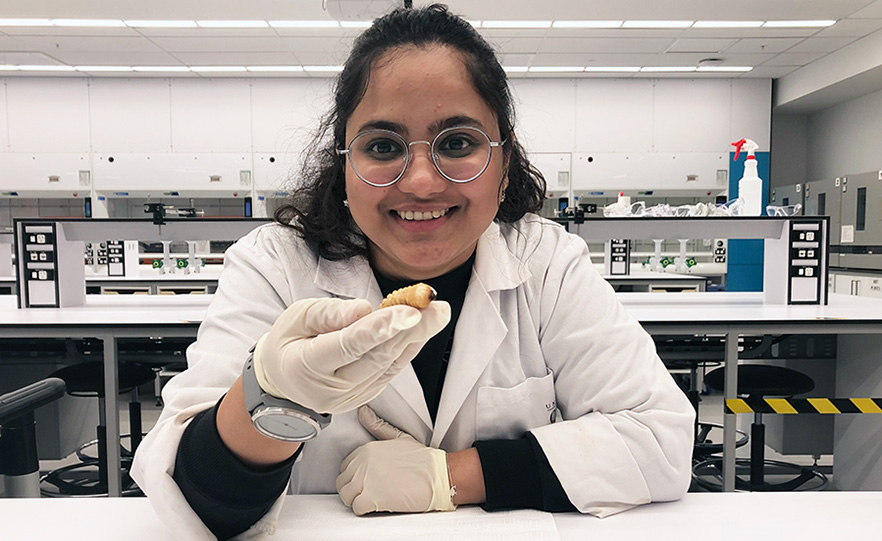 Ruchita Kavle in a laboratory holding a large grub image
