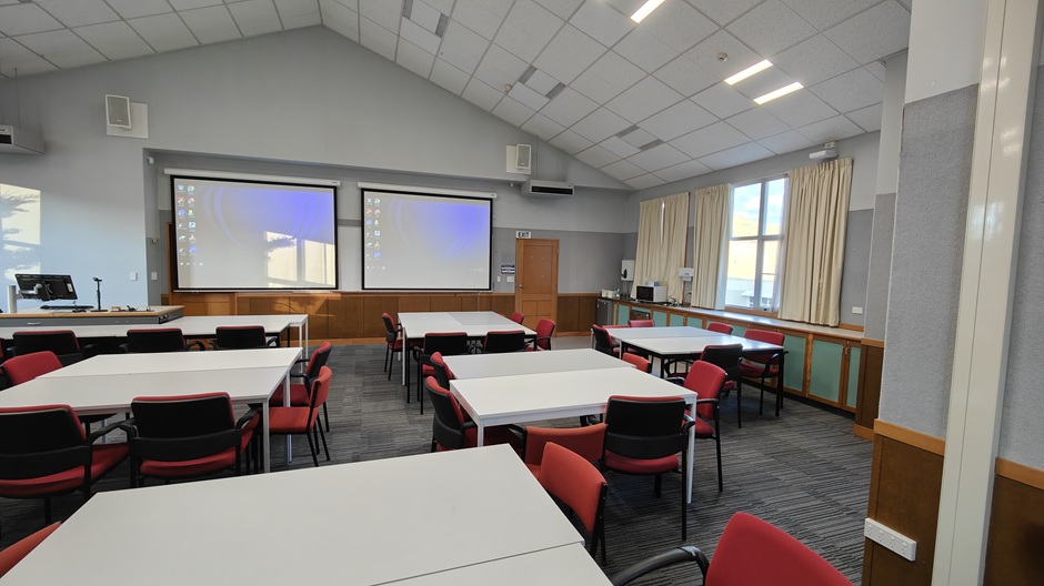 A view of Ōwheo building seminar room 206, showing tables and chairs in groups