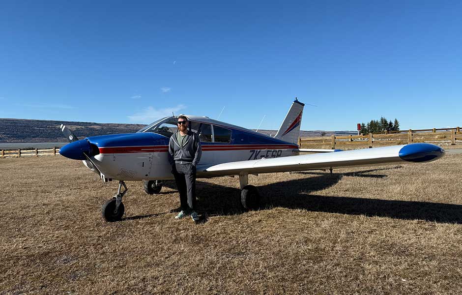 A man standing in a field next to a small airplane 