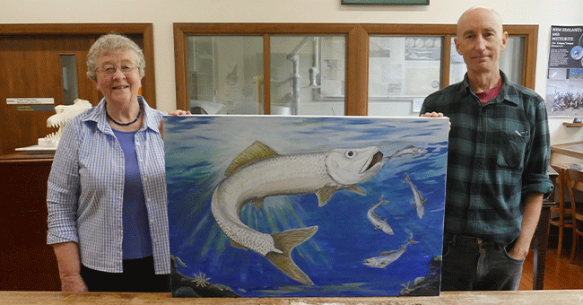 two people holding a painting of a fish