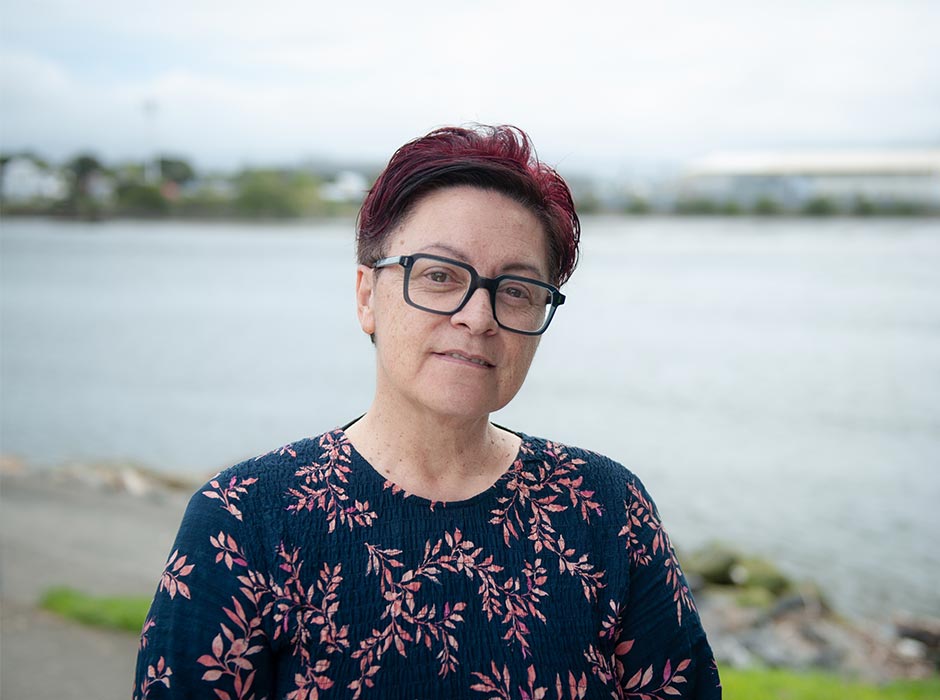A photo of Cheryl Davies taken outside against a backdrop of water.