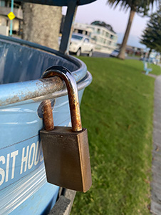 A rusty padlock on the edge of an outdoor rubbish bin image