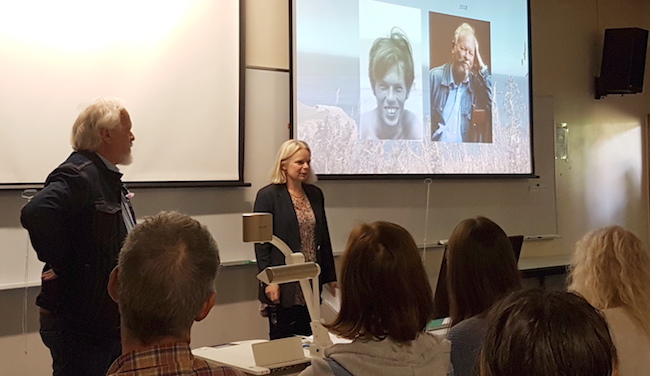 Professor Catherine Day and Associate Professor Russell Poulter stand in front of an audience of colleagues and students.