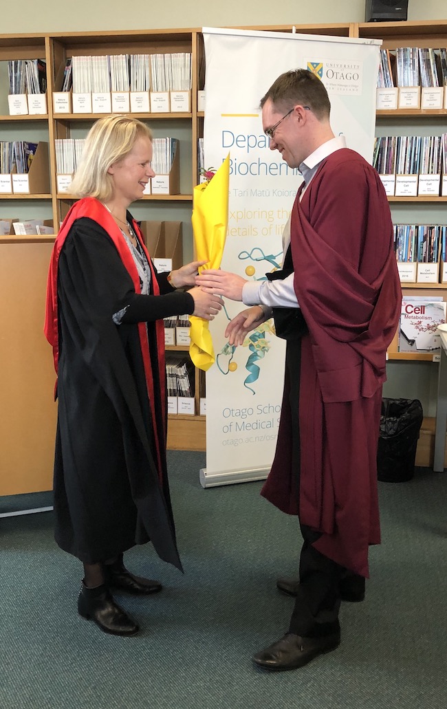 HOD Prof Catherine Day presents PhD graduate Tyler McInnes with a bouquet of flowers at the Biochemistry graduation morning tea.