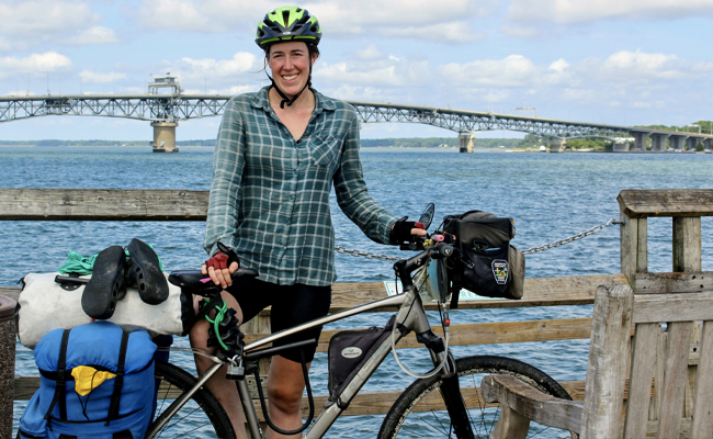 woman with a bike standing in front of a bridge 