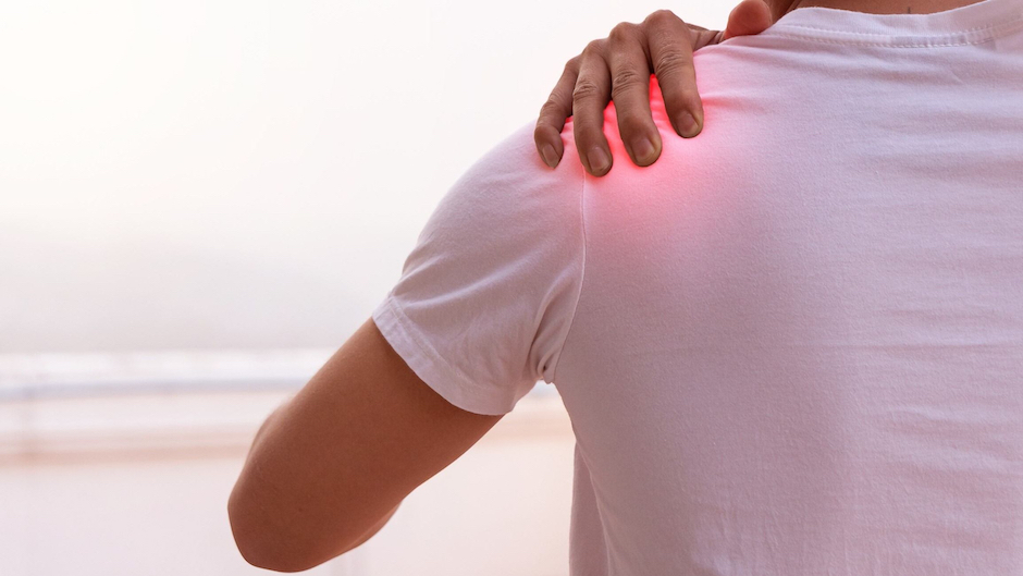 Man in white tee shirt grasping his left shoulder