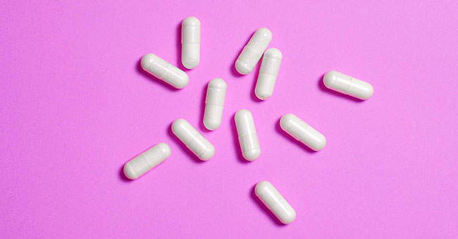 White-pills-on-pink-background