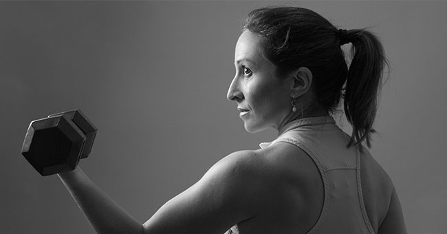 a woman holding up one single weight