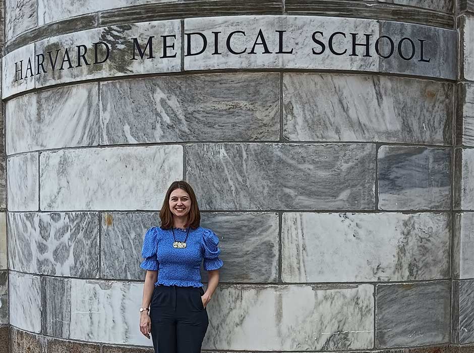 A woman standing in front of a Harvard sign 