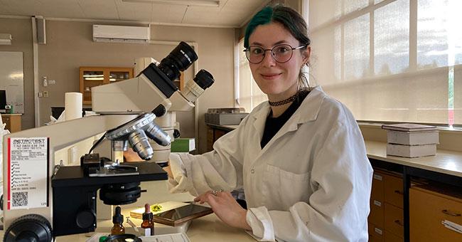 a woman sitting using a microscope 