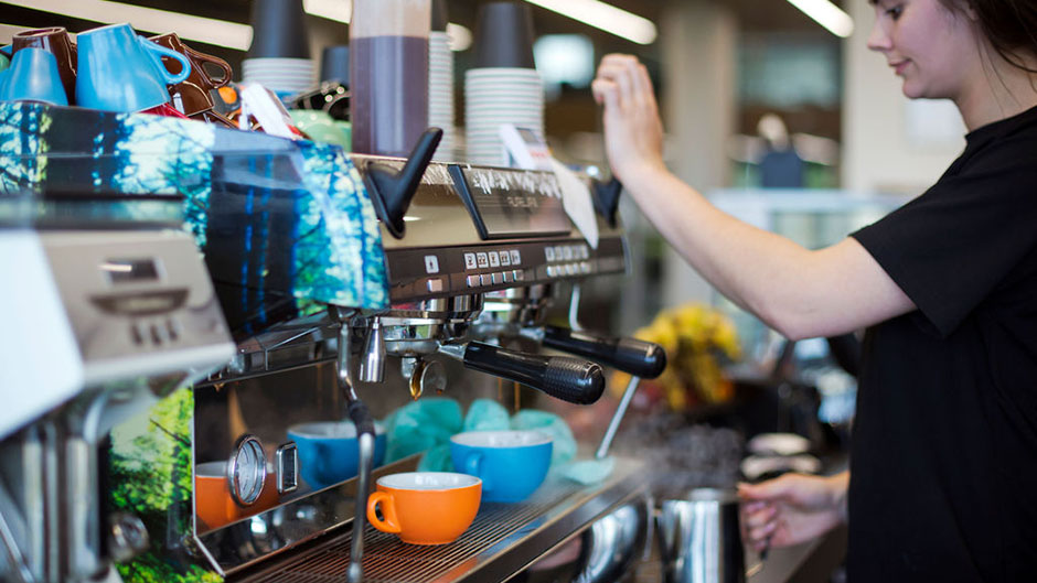 A barista operating a coffee machine at Te Mātiti café