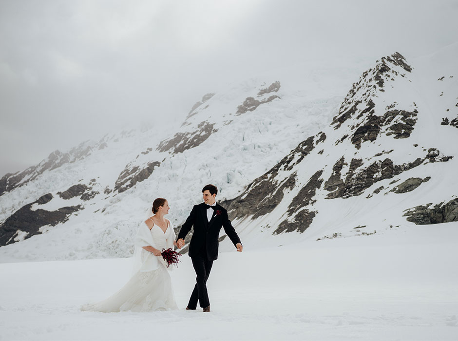 two people in wedding attire standing on a glacier 