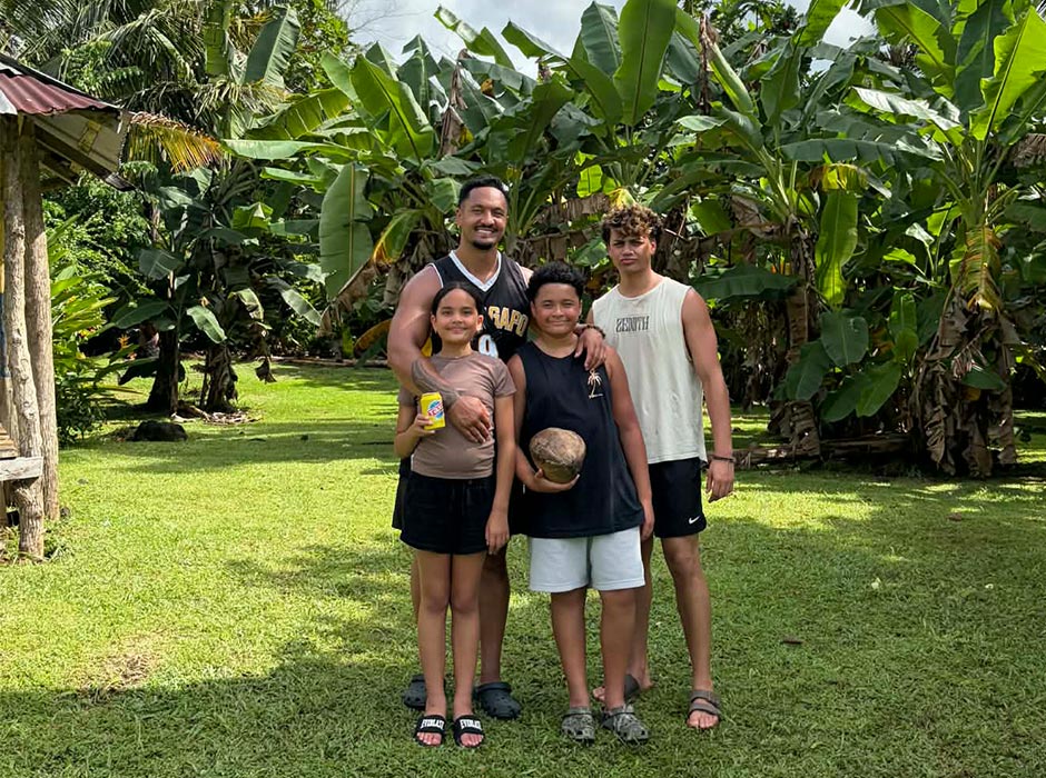 A man standing with his three children - two sons and a daughter.