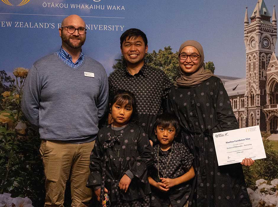 five people standing next to each other, three adults and two children, all smiling
