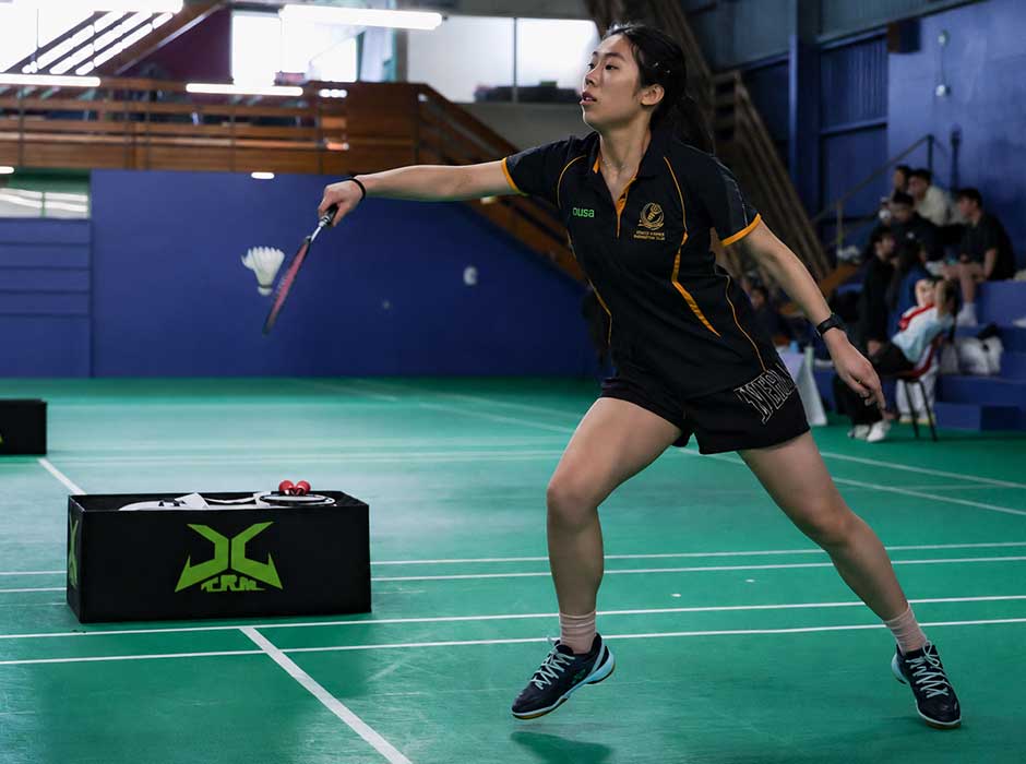 A woman on a court stepping forward to hit a shuttlecock 