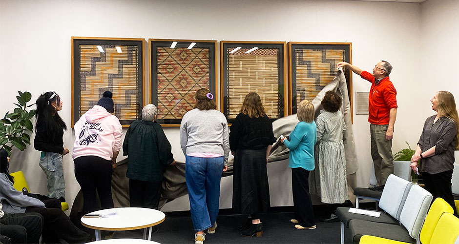 Human Nutrition kaimahi unveil the four tukutku panels in the staffroom.