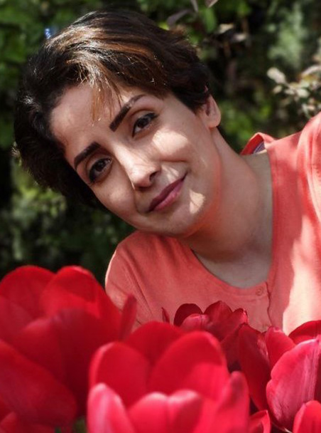Yelda Boroushaki in front of red flowers.