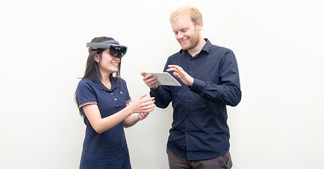 Woman using occulus with a man standing beside.