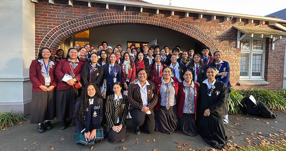 A group photo of young Pacific people in school uniforms gathered outside the University of Otago Pacific Islands Centre