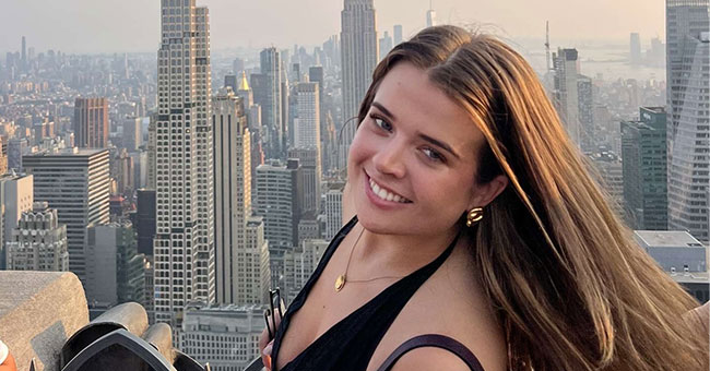 A woman standing atop a building with the new york skyline in the background 