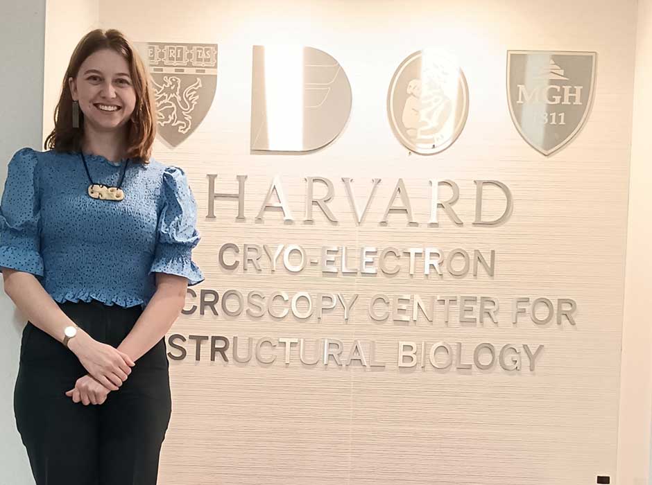 A woman standing next to a Harvard sign