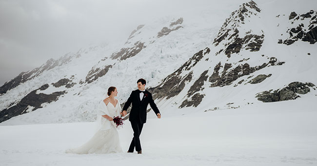 two people in wedding attire standing on a glacier 
