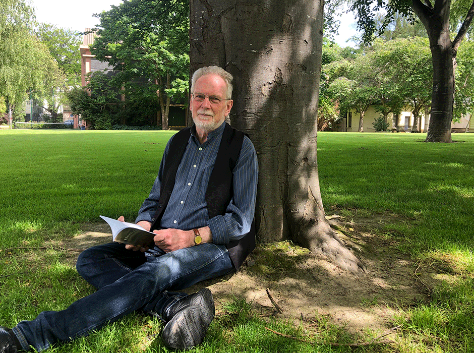 a man sitting under a tree reading a book 