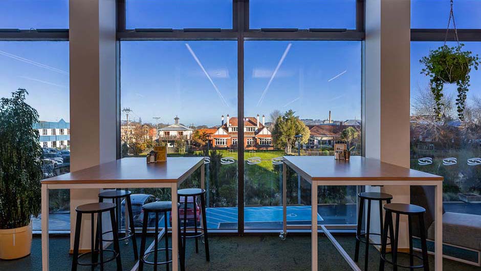 Tall tables and stools at Te Matiti cafe with a view towards the Water of Leith
