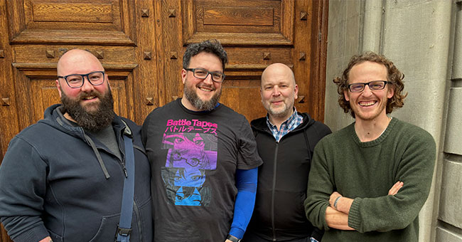 Four men pose for a photo outside the Zoology Department's Marples Building.