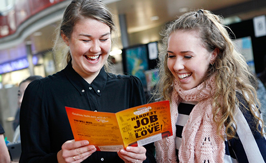 Two people reading a pamphlet and smiling