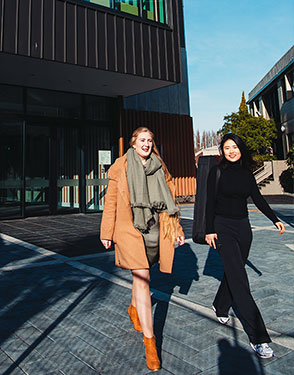 Two students walking outside the School of Performing Arts building