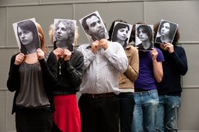Prof Jamin Halberstadt with students holding monochrome photos in front of their faces