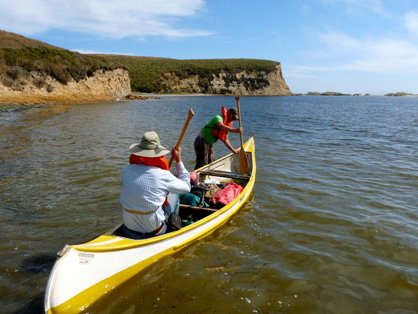 Robert W. Boessenecker and Richard Hilton departing in a canoe. Sandsotne cliffs in the background