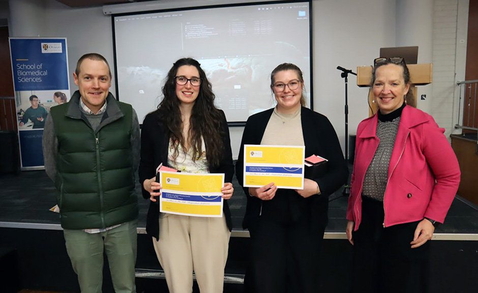 Two students: Tyla Alexander and Hazel Sisson holding their certificates, with Peter Mace and Lisa Matisoo-Smith on either flank.