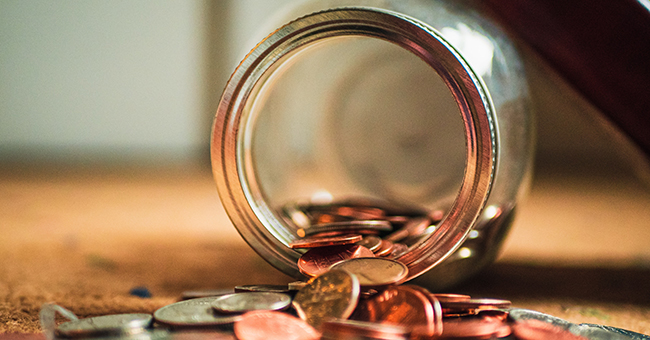 Coins spilling out of a glass jar thumbnail