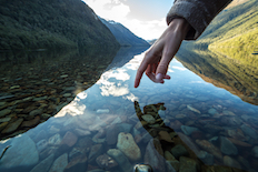 Hand reaching to touch a river