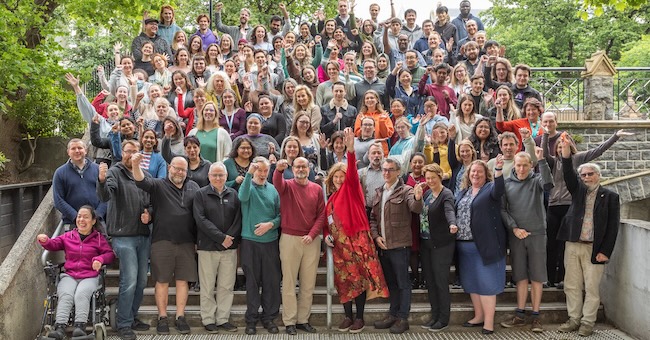 Group photo of about 100 Department of Biochemistry staff and students posing together with hands in the air