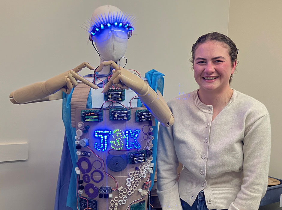 A woman standing next an outfit on a mannequin 