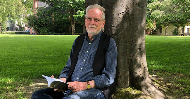 a man sitting under a tree reading a book 